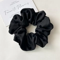 Close-up of black satin scrunchie with textured polka dots and pleated fabric design - Black Polka Dot Style