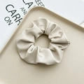 Nahaufnahme eines cremefarbenen Leder-Scrunchies mit weichen Falten auf Tablett - Leder Cremeweiß