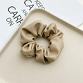 Detail eines khakifarbenen Kunstleder-Scrunchies mit weichen Falten und Textur - Leder Khaki