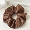 Détail d'un chouchou en cuir PU marron montrant une texture brillante et des coutures - Marron