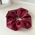 Détail de chouchou en cuir rouge foncé avec texture plissée riche et finition mate - Rouge
