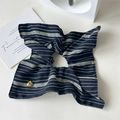 Dettaglio di un elastico in tessuto a righe blu navy con ciondolo a cuore in oro su bianco - Elastico Nero a Righe