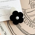 Detailansicht der schwarzen Samtblumen-Haarspange mit Perle auf Vintage-Hintergrund - Schwarz