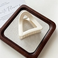 Dettaglio di una pinza per capelli triangolare color crema su un vassoio di legno rustico - Pinza Triangolo Sottile (Bianco Crema)
