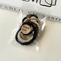 Dettaglio di elastici a spirale dai toni della terra in busta con adesivo di grazie - Corda per Capelli Papillon Cuore (5792107738406)