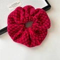 Detailed close-up of a red knitted scrunchie with diamond patterns and warm yarn texture - Red and Black Plaid Knitted Scrunchie