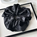Close-up detail of black scrunchie with metallic gloss texture and pleated design - Textured Pleated Black