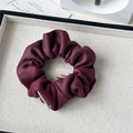 Close-up of a burgundy suede scrunchie with pleated texture and a small fabric tag - Retro Suede Wine Red