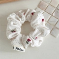 Detailed macro view of cream floral scrunchie with cherry prints and textured fabric - White Red Floral