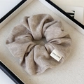 Macro shot of oatmeal ribbed knit scrunchie with a white Hand Made decorative label - Khaki Knitted Scrunchie