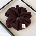 Detailed close-up of dark brown knitted scrunchie with handmade fabric label on tray - Brown Knitted Scrunchie