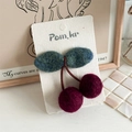 Close-up of handmade felt cherry hair clip featuring deep red wool balls and green leaves - Cherry Hair Clip