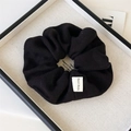Detail of black knitted scrunchie with rib texture and Hand Made fabric label in a tray - Black Knitted Scrunchie