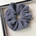Detailed view of dusty blue plush scrunchie with soft velvet texture on display tray - Small Plush Blue