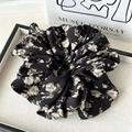 Close-up of a large floral scrunchie with vintage patterns on a fabric display tray - Tulip Black