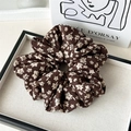 Detailed macro view of large floral brown scrunchie with elegant vintage textile texture - Floral Coffee