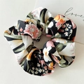 Detailansicht eines großen Satin-Haargummis mit Blumenmuster auf beigem Grund - Schwarz Großer Floral Haargummi