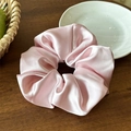 Detailed view of pink satin scrunchie with silky texture and folds on a wooden surface - 16cm Pink