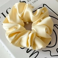 Close-up of a pale yellow satin scrunchie with elegant faux pearl embellishments - Light Yellow