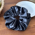 Dettaglio dell'elastico in raso nero con trama in seta su fondo in legno scuro - 16cm Nero
