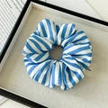 Detail of blue and white striped scrunchie with an elegant label on a textured tray - Thick Light Blue Stripes
