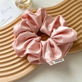 Detail of pink silk satin scrunchie with brand logo tag on a wooden wave tray - Sweet Pink