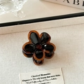 Detailansicht einer Vintage Bernstein-Schwarz Blumen-Haarklammer auf texturiertem Grund - Kleine Schwarze Blume