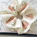 Nahaufnahme von beigem Haarband mit Blumenstickerei und weißem Spitzenbesatz - Bestickte Schleife (Off-White)