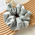 Silky satin scrunchie in light blue with premium woven label on wave tray - Chilly Blue