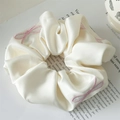 Dettaglio dell'elastico in raso color crema con fiocchi ricamati rosa su rivista - Bianco Crema