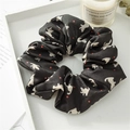 Detail of black silk satin scrunchie with white cat prints and red dots in a tray - Cat Black