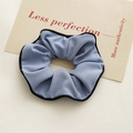 Nahaufnahme von hellblauem Scrunchie mit Fischgrätenmuster und schwarzer Paspelierung - Blau