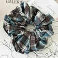 Dettaglio di un elastico per capelli a scacchi marrone e blu su un piatto di ceramica bianco - Quadri Blu