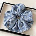 Detailed view of blue denim hair scrunchie with white floral embroidery and fine stitching - Dark Blue Hollow Embroidery