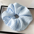 Detail of blue and white checkered scrunchie with pleated texture on white fabric base - Light Blue Gingham Stripe