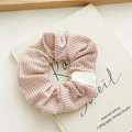 Gros plan sur chouchou en velours côtelé rose avec texture verticale et étiquette blanche - Rose