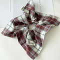Détail d'un chouchou à carreaux rouge et bleu avec bouton décoratif et étiquette fait main - Style Foulard Écossais Rouge