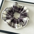 Détail d'un chouchou en tissu à carreaux avec bouton gris et étiquette fait main - Chouchou Écossais Violet Avec Bordure