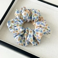 Gros plan détaillé du chouchou en mousseline à fleurs bleues et orange avec élastique - Style de base / Tie-dye Bleu