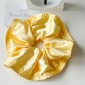 Detailed close-up of bright yellow satin scrunchie showing glossy texture and ruffle edges - Yellow
