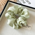 Close-up of light green tencel silk scrunchie with fine texture in a display box - Green