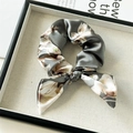 Detailansicht eines Satin-Haargummis mit Blumenmuster und Hasenohren auf Leinentablett - Schleifen-Scrunchie / Grau