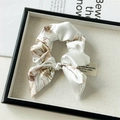 Detail eines elfenbeinfarbenen Satin-Haargummis mit Blumenmuster und Schleife - Schleifen-Scrunchie / Weiß