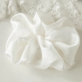 Close-up of pearl white oversized chiffon scrunchie with soft ruffled fabric texture - Beige