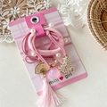 Dettaglio del set di elastici per capelli rosa con nappe e perle su scheda espositiva - Rosa Vintage