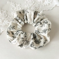 Detailopname van de crèmekleurige kant haarelastiek met elegante zwarte bloempatronen - Zwart-Wit Bloemen Kant Scrunchie Stijl