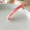 Vista macro della clip in acetato rosa con base in metallo dorato e incisione Barrette La France - Rosa