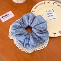 Detailed shot of blue floral scrunchie with white lace edges on wooden surface - Lace Style / Blue