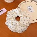 Gros plan d'un chouchou floral élégant avec bordure en dentelle sur bois - Grand Style Dentelle / Beige