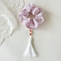 Vue détaillée du chouchou floral avec de longs pompons blancs et perles rouges - Rose